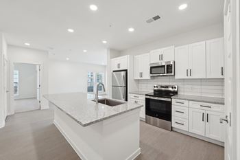 A modern kitchen with white cabinets and stainless steel appliances.